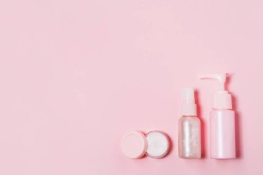 Pembe arka planda kozmetik şişe kapları.