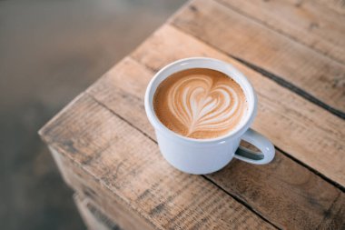 Ahşap arka planda latte sanatıyla bir fincan kahve..