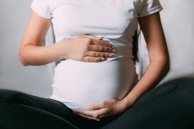 Hamile kadının karnı lotus bulunduğu otururken dokunmadan yakın çekim.