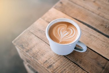 Ahşap arka planda latte sanatıyla bir fincan kahve..