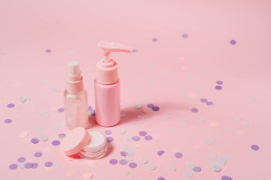 Pembe arka planda kozmetik şişe kapları.