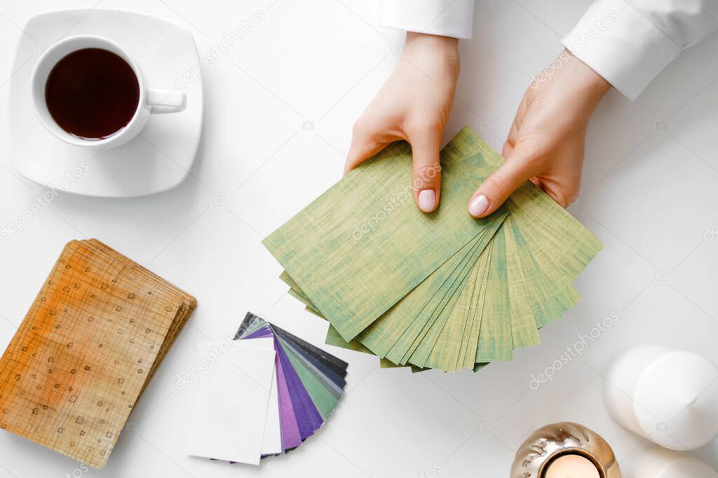 Metaphorical associative cards. Consultation of a psychologist. Young woman holds a deck in hands and chooses a card. Flat lay composition.
