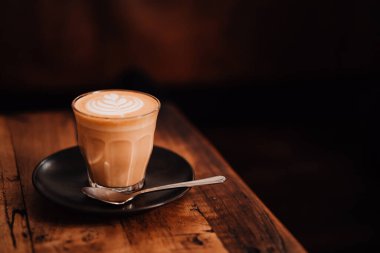 Hipster kahve dükkanının ahşap masasında düz beyaz kahve fincanı. Kopyalama alanı, düşük tuşlu ışıklandırma.