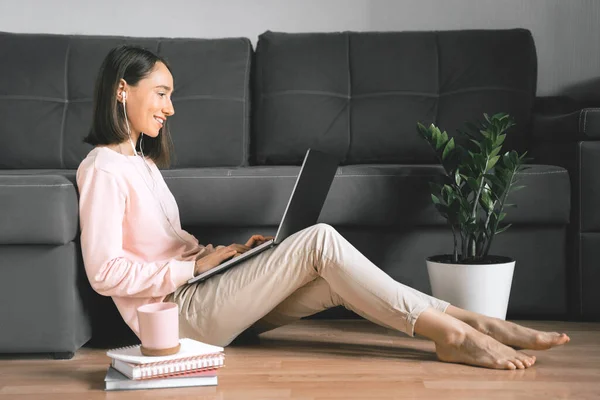 Молодая женщина сидит на полу и использует ноутбук. Лицензионные Стоковые Фото