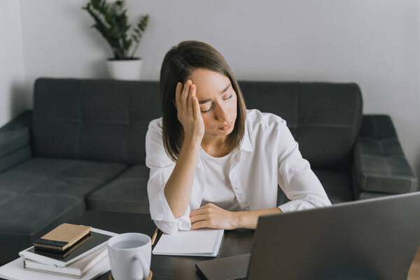 Портрет уставшей молодой женщины с ноутбуком в домашнем офисе
.