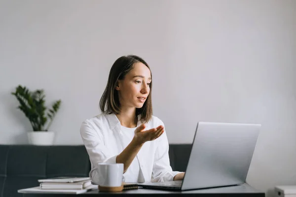 Junge Frau sitzt am Tisch und benutzt Laptop. — Stockfoto