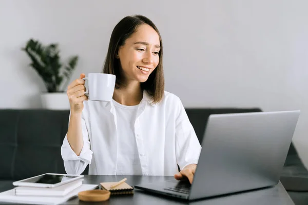 Junge Frau sitzt am Tisch und benutzt Laptop. — Stockfoto