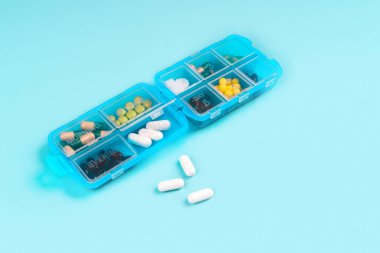 Mavi renkli arka planda mavi bir hap kutusunda reçeteli ilaç ve vitaminler. Düz konum fotoğrafı, metin için boşluk.