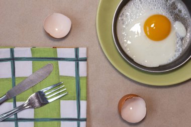 Tavada yumurta ve yeşil tabak, çatal ve bıçak, avokado, yumurta kabuğu, bulaşık havlusu..