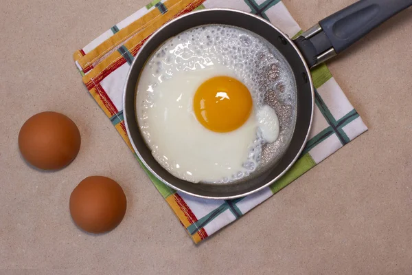 Jajko smażone na patelni, skorupki jaj, ręcznik do naczyń. — Zdjęcie stockowe