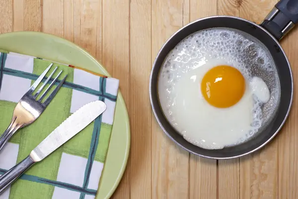 Вареный стол с жареным яйцом, посудой, ножом и вилкой. — стоковое фото