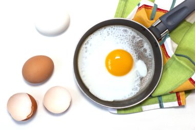 Tavada yumurta, bulaşık havlusu ve beyaz arka planda haşlanmış yumurta..