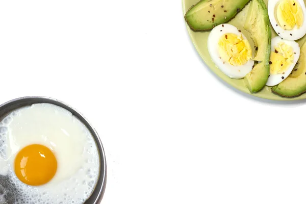 Smażone jajko na patelni, zielony talerz z gotowanym jajkiem i awokado, ręcznik kuchenny, widelec na białym stole — Zdjęcie stockowe