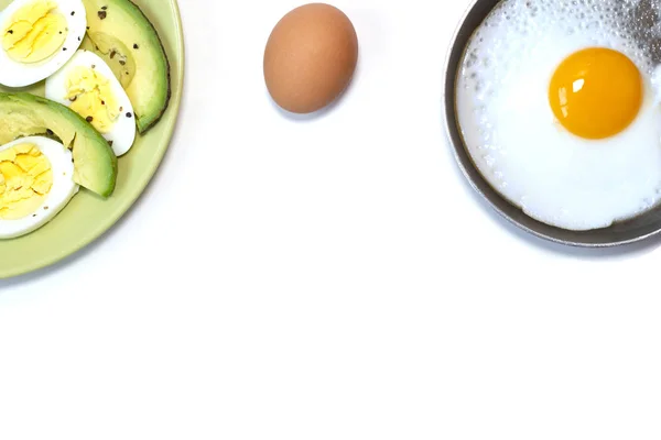 Gebakken ei op de pan, groene plaat met gekookt ei en avocado op de witte tafel Stockafbeelding