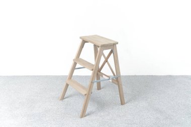 Aydınlık odada tahta merdiven ve tabure.