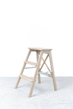 Aydınlık odada tahta merdiven ve tabure.