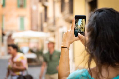 Verona 'da tatildeki turist kız tipik bir İtalyan caddesinin fotoğrafını çekiyor.
