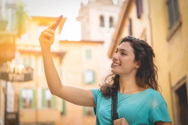 Toeristisch meisje op vakantie in Verona neemt een selfie op een typische straat — Stockfoto