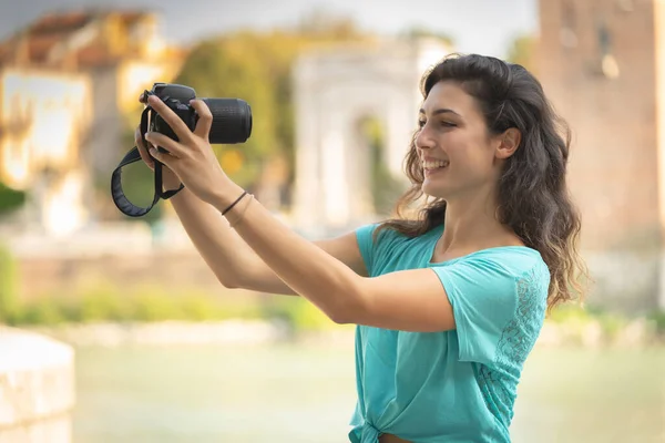 Glimlachend meisje in een Italiaanse stad met een camera in haar hand. — Stockfoto