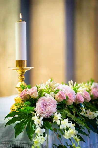 Bougie sur l'autel avec des fleurs roses — Photo