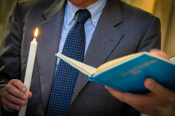 Read the bible with the light of the singer at a baptism — Stock Photo, Image