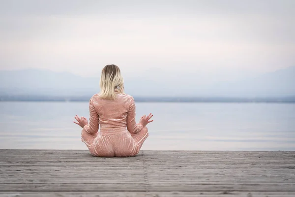 Lány ül egy mólón meditál, jóga, nyugi Stock Kép