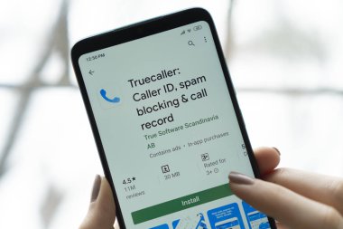 New York - January 9, 2020: Truecaller app on a smartphone with a finger above the screen.  Truecaller is a application for blocking spam calls and SMS.
