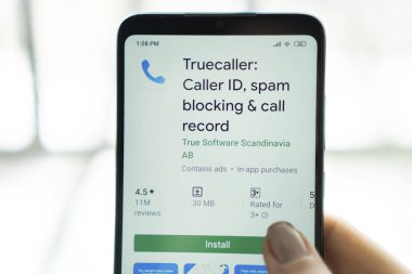 New York - January 9, 2020: Truecaller app on a smartphone with a finger above the screen.  Truecaller is a application for blocking spam calls and SMS.
