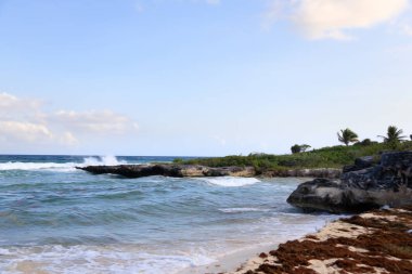 Sahilde sıcak bir ışık ve kayalar.