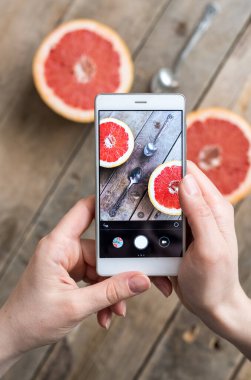 Meyve fotoğrafına yakın çekim. Kızın elleri beyaz telefonu tutuyor ve...