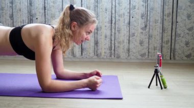Kız spor blogcusu egzersiz yapıyor ve canlı yayında telefon kamerasına yönlendiriyor.
