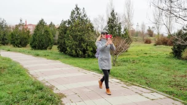 Молодая девушка ведет прямую трансляцию в осенний парк, образ жизни и технологии концепции — стоковое видео