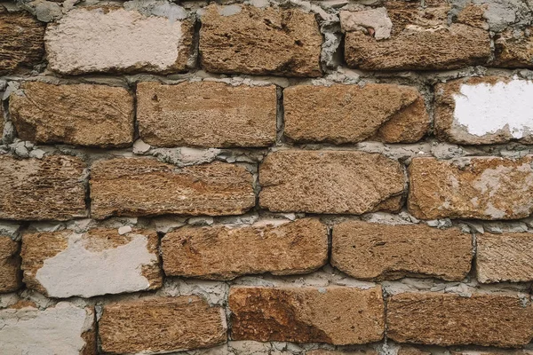 Brown old stone wall close-up of a block of shell rock in grunge style. Vintage texture of the brickwork. Background for the subject flat lay. Concept of construction and interior design. Copy space