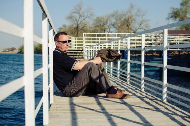 Elinde ceketi olan bir adam açık havada rıhtımın zemininde oturuyor ve ne yazık ki uzaklığa bakıyor. Stres, orta yaş bunalımı, yalnızlık ve kriz kavramı..