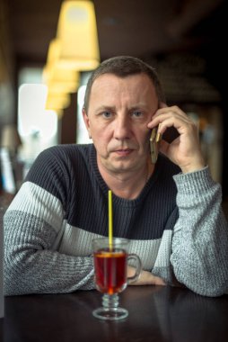 Samimi bir kafede cep telefonuyla konuşan kazaklı ciddi bir adam. Bir fincan çay eşliğinde sorunları çözüyoruz. Modern teknoloji ve mobil iletişim kavramı