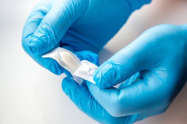 Eldivenli bir doktor anal ya da vajinal kullanım için fitil açar. Candida tedavisi için tıbbi mumlar, ardıç kuşu, hemoroit, iltihap ve ateş. Beyaz arka planda etkili uyuşturucu