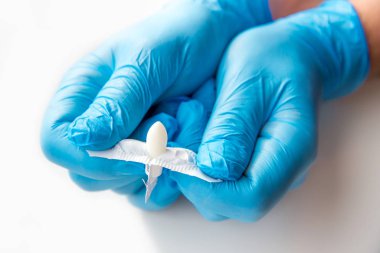 Eldivenli bir doktor anal ya da vajinal kullanım için fitil açar. Candida tedavisi için tıbbi mumlar, ardıç kuşu, hemoroit, iltihap ve ateş. Beyaz arka planda etkili uyuşturucu