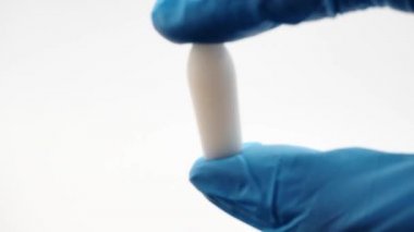 Mavi eldiven giyen doktorlarda anal ya da vajinal kullanım için beyaz fitil. Candida tedavisi için tıbbi mumlar, ardıç kuşu, hemoroit, iltihap ve ateş. Etkili uyuşturucu yakın plan