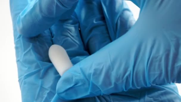 Suppositoire blanc pour une utilisation anale ou vaginale dans les mains du médecin portant des gants bleus. Bougies médicales pour le traitement de Candida, muguet, hémorroïdes, inflammation et fièvre. Gros plan sur les médicaments efficaces — Video