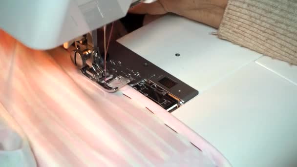 Adult woman seamstress sews from colored fabric on sewing machine.Hands close up. Woman makes a smooth machine stitch on wrong side. Making clothes and sewing bed linen at home or in a garment factory — Stock Video