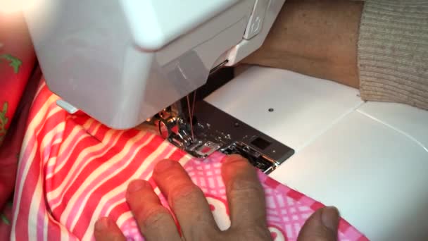 Adult woman seamstress sews from colored fabric on sewing machine.Hands close up. The woman makes a smooth machine line. Making clothes and sewing bed linen at home or in a garment factory — Stock Video