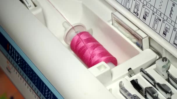 Bobine rose de filetage dans un gros plan de machine à coudre. Une couturière femme fait un point de machine lisse. Fabrication de vêtements et de linge de lit à coudre à la maison ou dans une usine de vêtements — Video