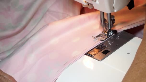 Adult woman seamstress sews from colored fabric on sewing machine.Hands close up secure line. The woman makes a smooth machine line. Making clothes and sewing bed linen at home or in a garment factory — Stock Video