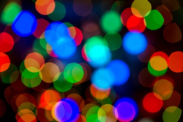 Noël fond lumineux coloré. Festive abstraite bokeh déconcentré grandes guirlande de lumières colorées sur fond noir. Espace de copie — Photo