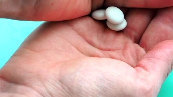 La mujer vierte pastillas en su mano para beber y envenenarse. Concepto de sobredosis, medicina y atención médica. Una dosis para la muerte. Exceso de drogas en el tratamiento moderno. Cápsulas sobre fondo azul — Vídeo de stock