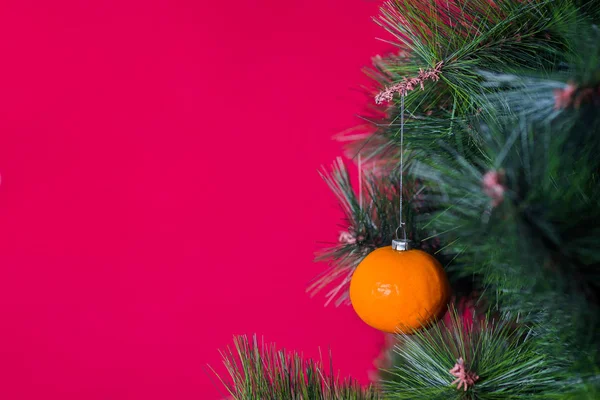 Wegański koncert świąteczny. Drzewo ozdobione jest świeżymi owocami. surowy mandarynka na gałąź choina na czerwienny tło. Idea minimalizmu i ekologicznego świętowania bez marnotrawstwa. Przestrzeń kopiowania — Zdjęcie stockowe