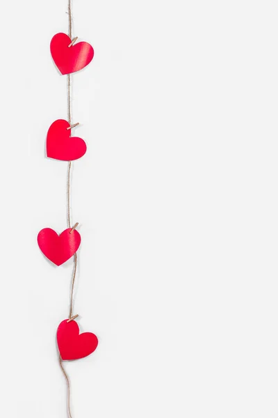Een slinger van rode harten op een witte geïsoleerde achtergrond. Natuurlijk touw en wasknijpers. Het concept van erkenning in liefde, romantische relaties, Valentijnsdag. Kopieerruimte — Stockfoto