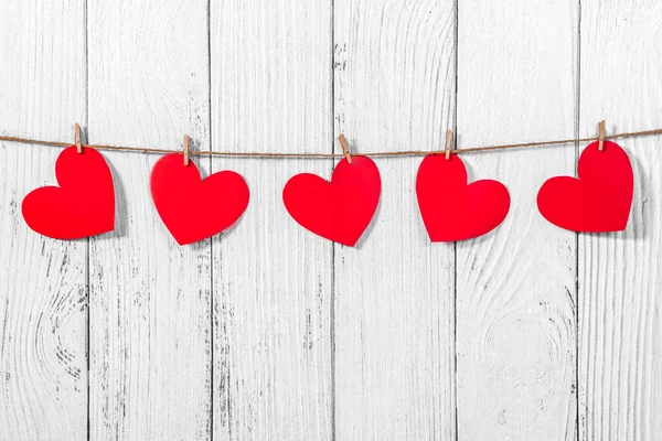 Fond en bois peint en blanc avec une guirlande de cœurs rouges. Corde et pinces à linge naturelles. Concept de reconnaissance de l'amour, relations amoureuses, Saint Valentin en style grunge. Espace de copie — Photo