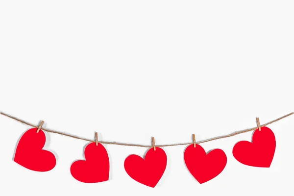 Garland of red hearts on a white isolated background. Natural rope and clothespins. The concept of recognition in love, romantic relationships, Valentines Day. Copy space