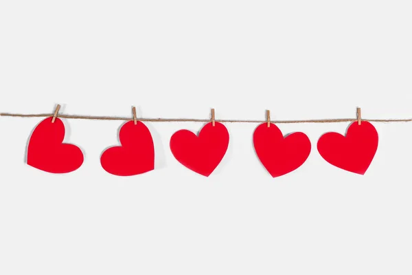 Een slinger van rode harten op een witte geïsoleerde achtergrond. Natuurlijk touw en wasknijpers. Het concept van erkenning in liefde, romantische relaties, Valentijnsdag. Kopieerruimte — Stockfoto
